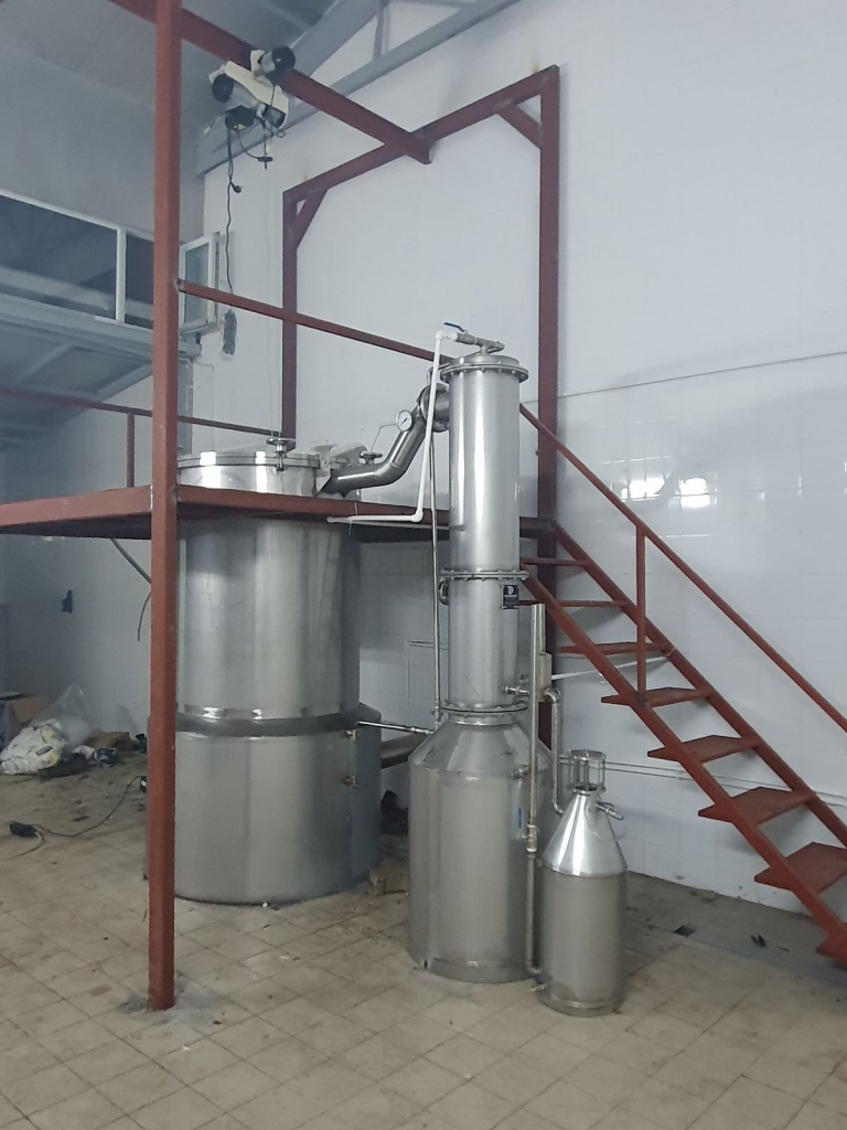 Unidad de destilación por vapor de acero inoxidable con plataforma de carga de acero rojo.