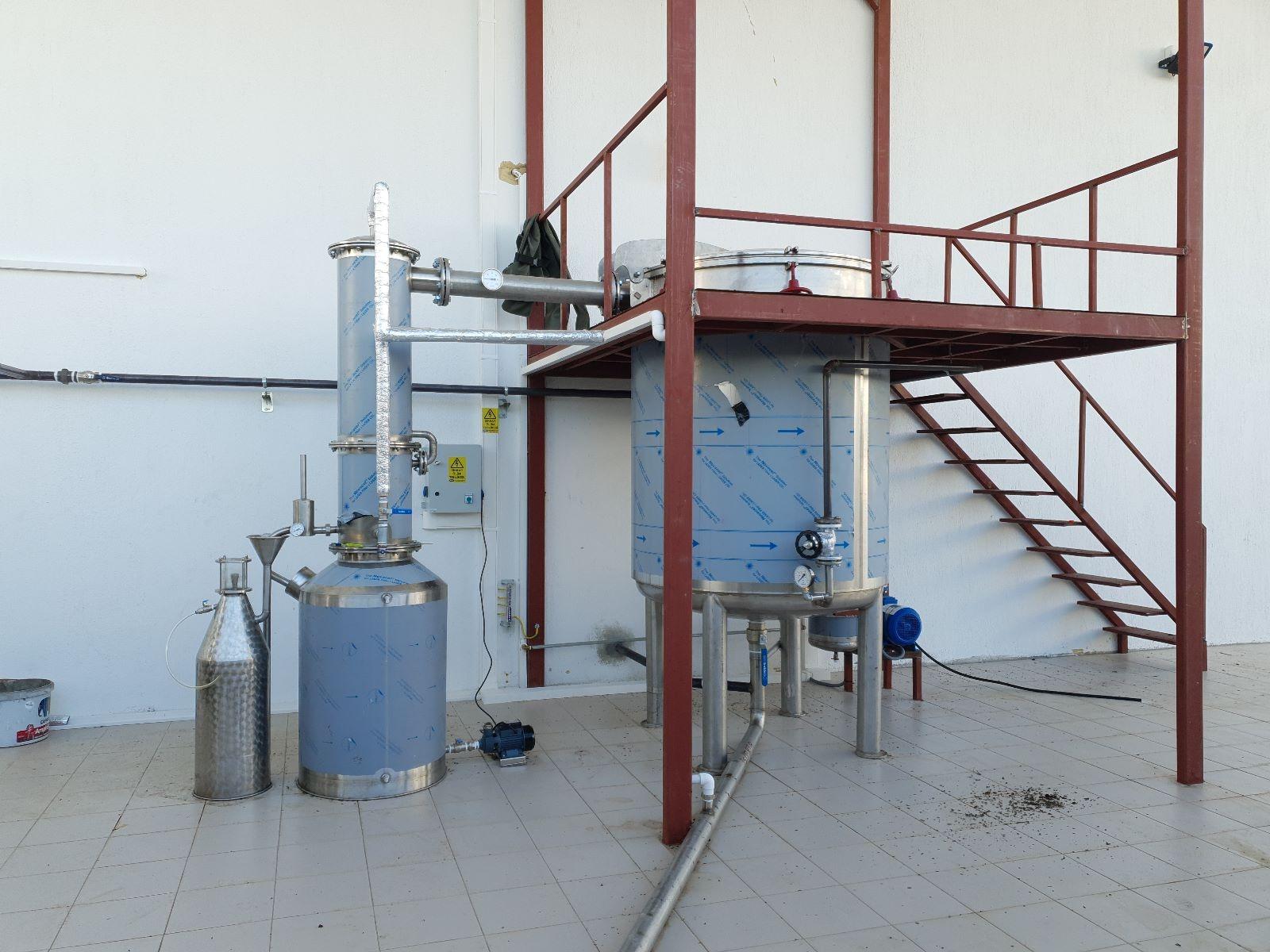 Stainless steel distillation still with a loading platform and stairs