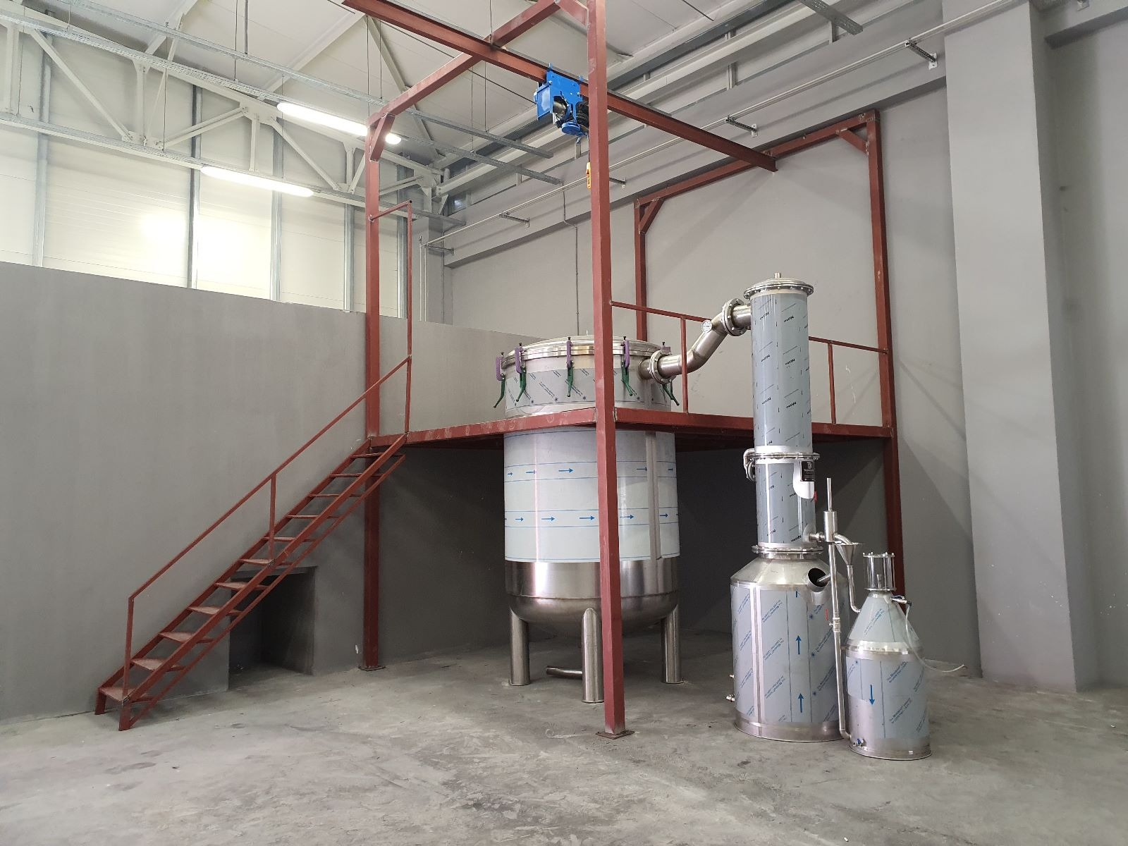 Stainless steel distillation still and condenser under a service platform