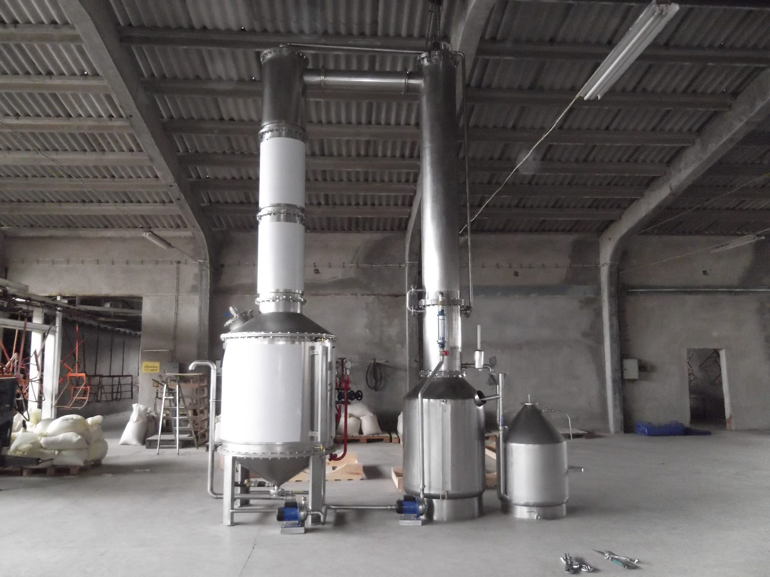 Distillation column with reboiler and product tanks in a production hall
