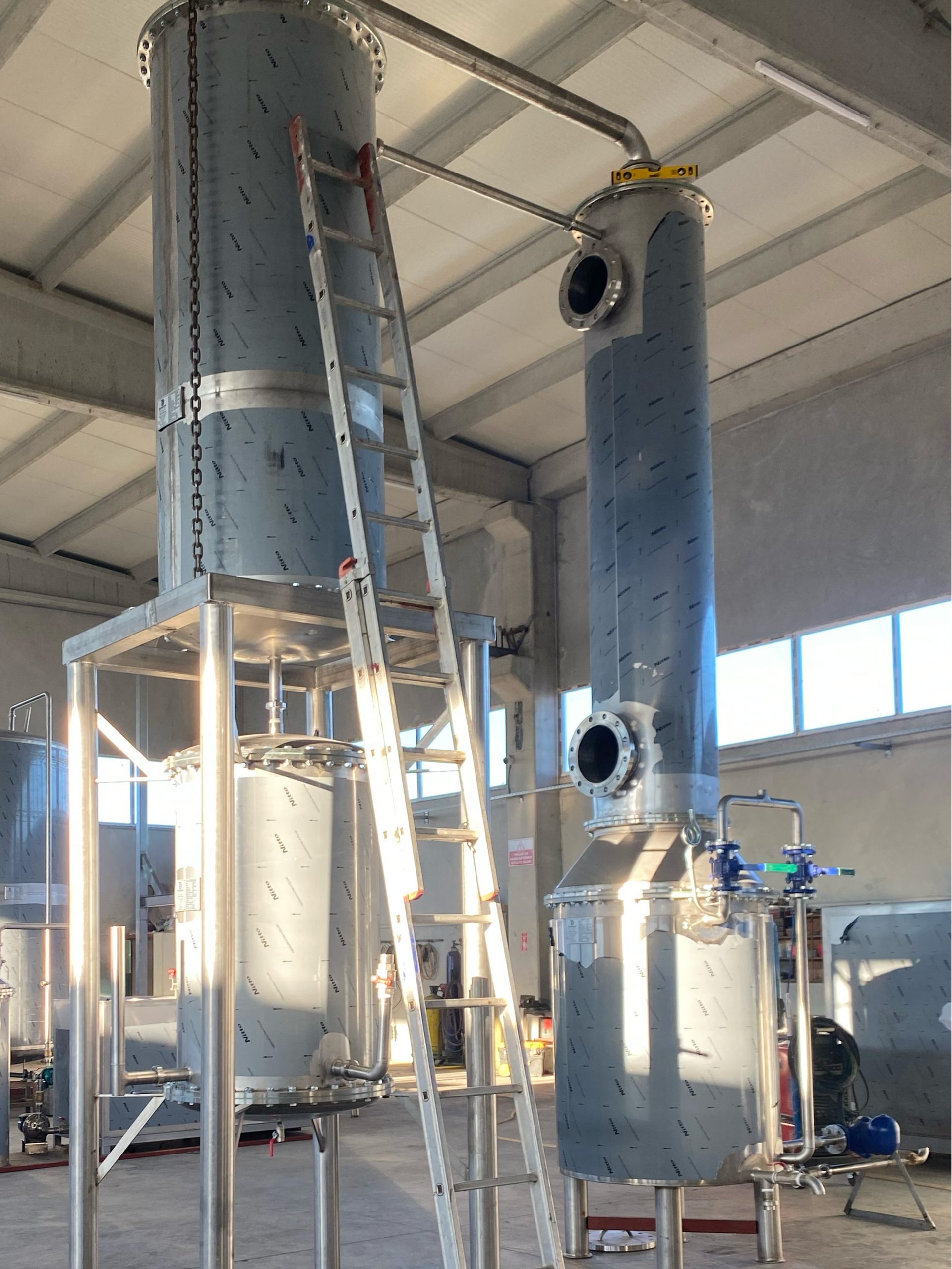 Stainless steel distillation column on a steel frame in the workshop