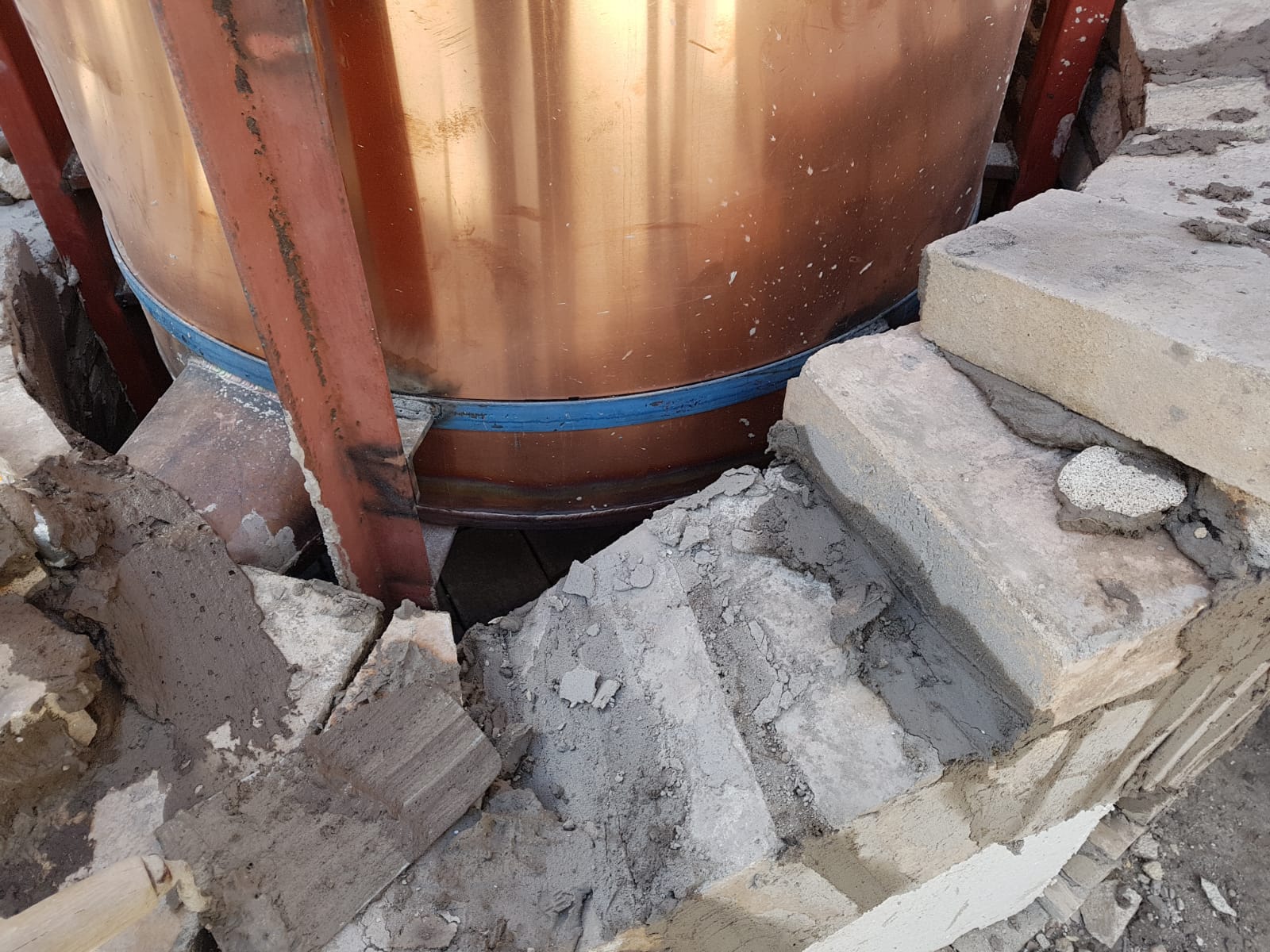 Masonry firebox being built around a wood-fired copper rose still