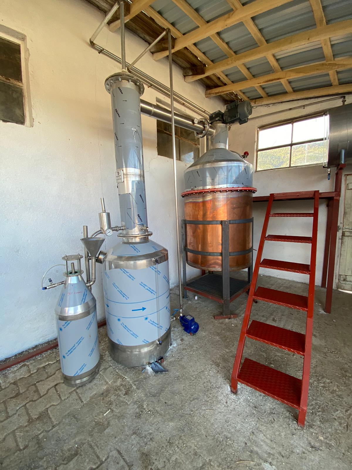 Copper rose distillation still with loading ladder and condenser