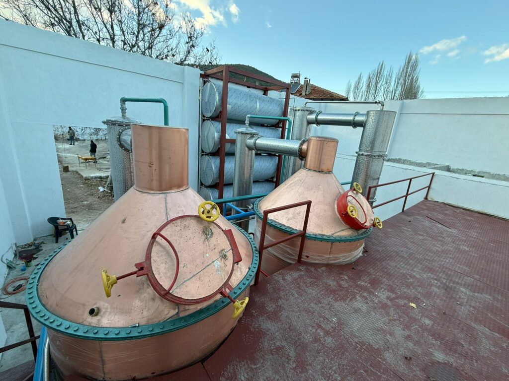 Rose Oil Distillation Plant with 2 copper distillation units, 1 cohobation system, stainless steel condensers, Florentine separators, and auxiliary storage tanks manufactured by Dünder Makine.