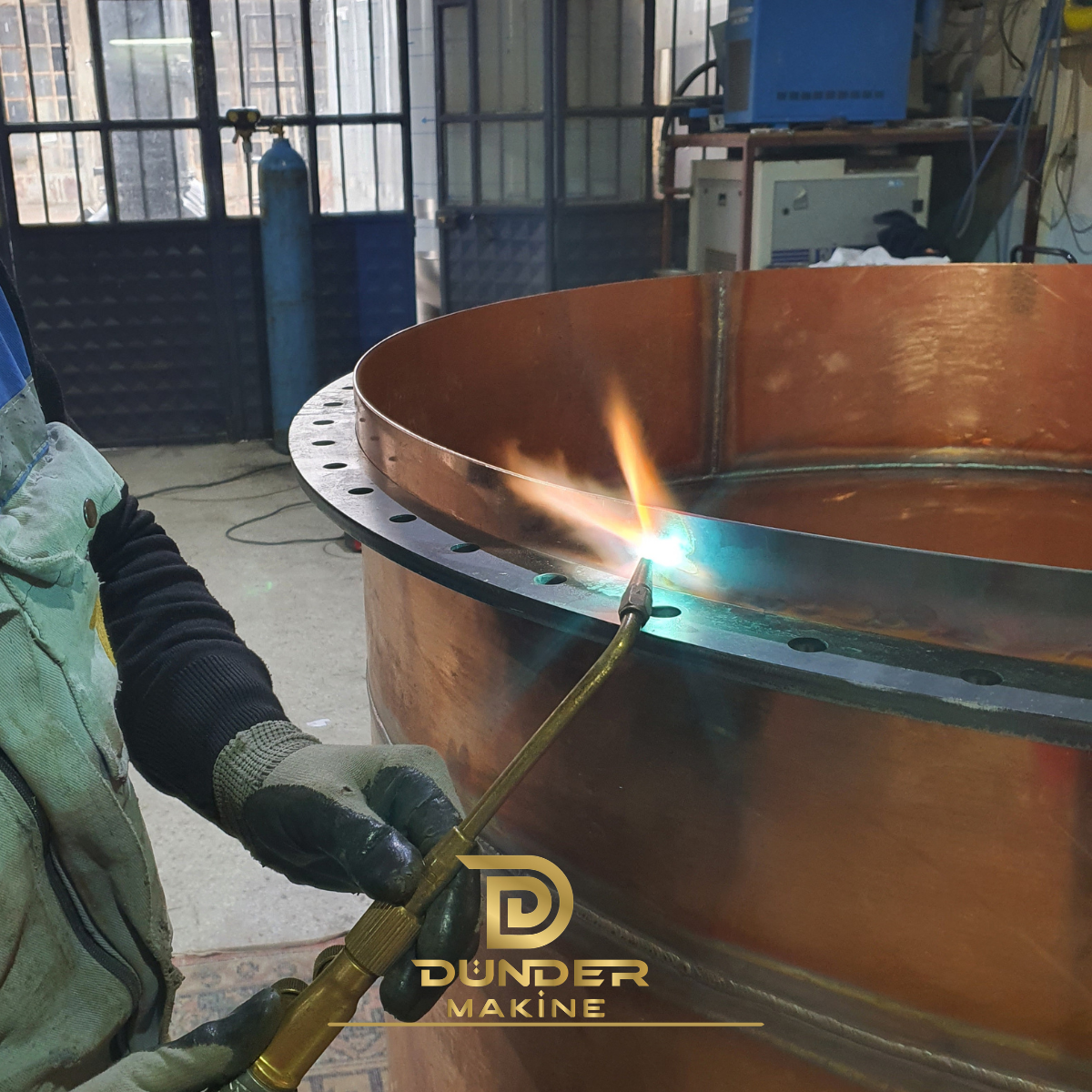 Un artesano calienta una lámina de cobre para dar forma a un alambique en el taller de Dünder Makine.