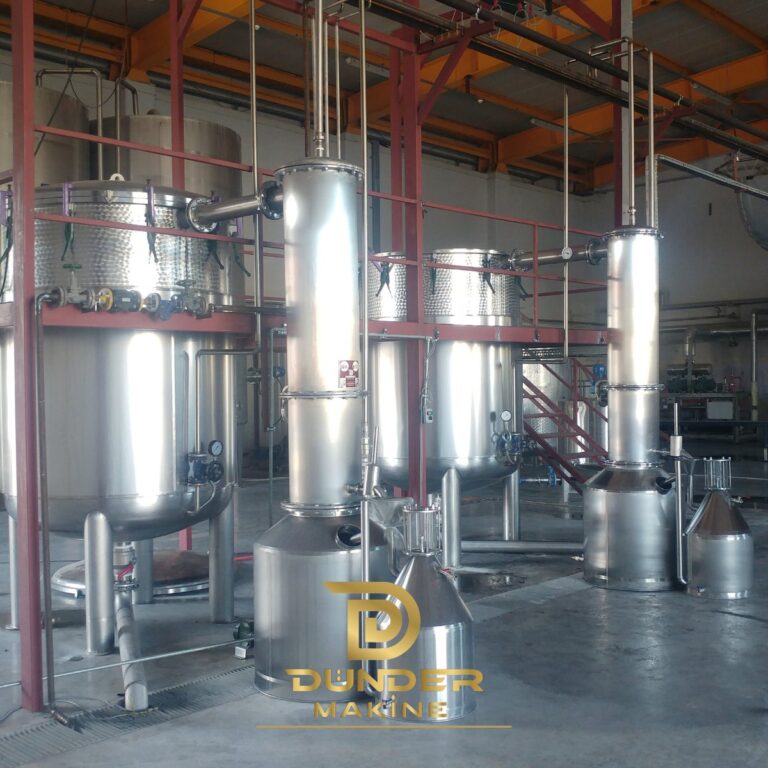 Steam and water distillation plant with stainless steel stills, columns and Florentine flasks on a red steel frame