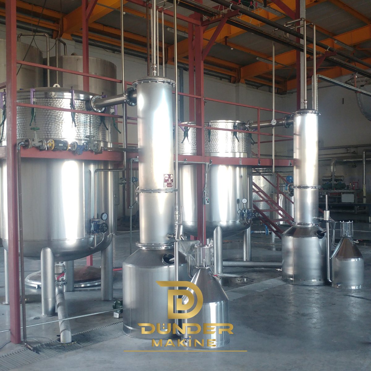 Steam and water distillation plant with stainless steel stills, columns and Florentine flasks on a red steel frame